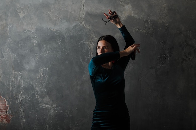 Mujer española adulta joven bailando flamenco sobre fondo gris de estudio vintage