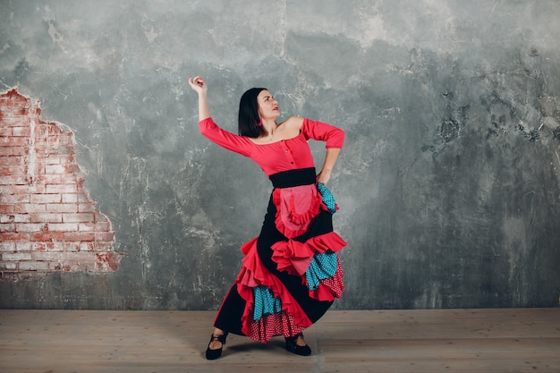 Mujer española adulta joven bailando flamenco sobre fondo gris vintage