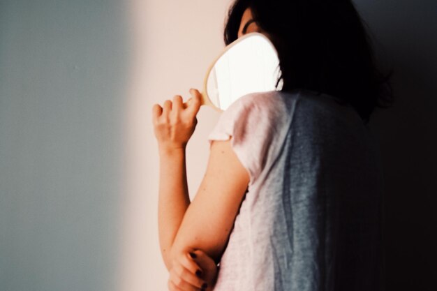 Mujer con un espejo contra la pared