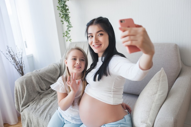 Mujer esperando feliz haciendo selfie a su marido. Ama de casa embarazada hablando por teléfono celular con su familia.