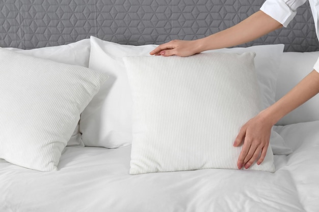 Foto mujer esponjando una almohada suave en el primer plano del dormitorio