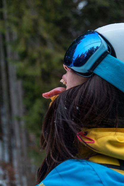 Mujer esquiador saca la lengua cogiendo nieve