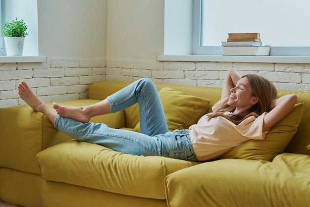 una mujer está acostada en un sofá con los pies en el sofá