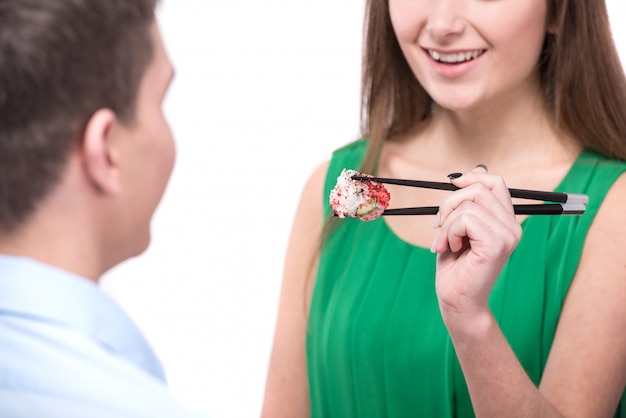 La mujer está alimentando a su novio con sushi.