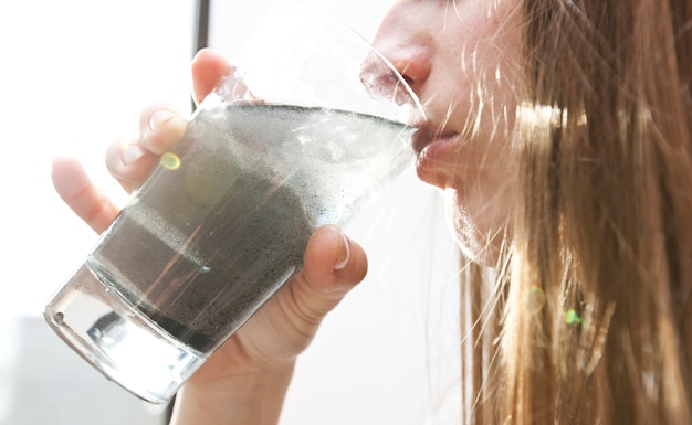 mujer está bebiendo agua sucia de vaso de vidrio