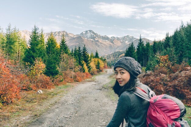 La mujer está caminando en la naturaleza colorida escénica del bosque y las colinas.