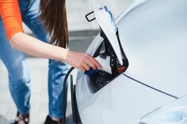 La mujer está cargando un coche eléctrico de alquiler