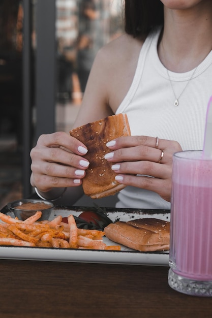 una mujer está comiendo un sándwich y un vaso de jugo