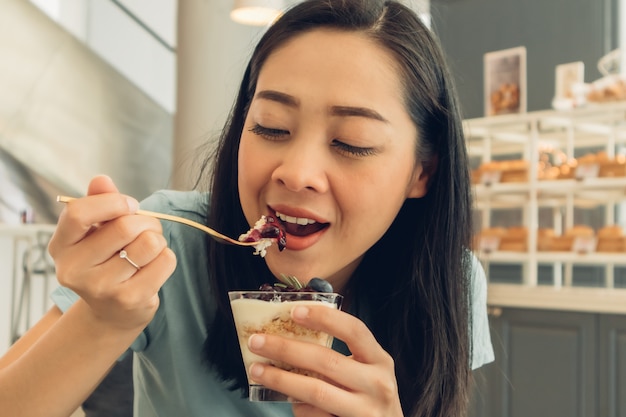 Mujer está comiendo su pastel en el café de la panadería.