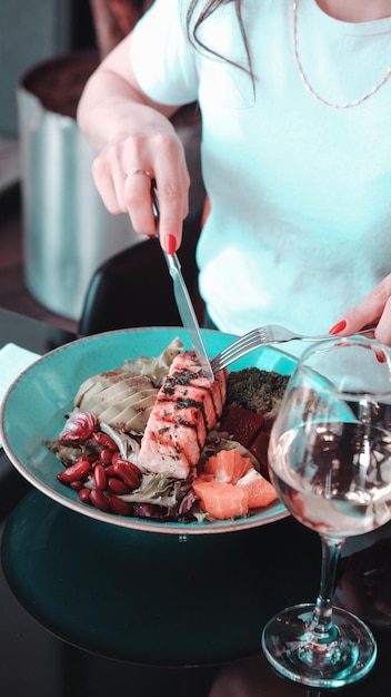 una mujer está cortando un pedazo de sushi con un vaso de vino