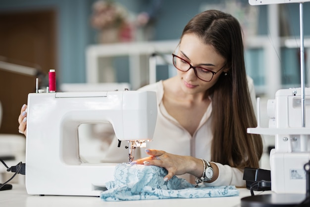 Una mujer está cosiendo con la máquina de coser eléctrica Taller de sastrería de moda