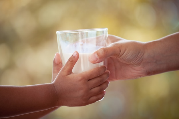 La mujer le está dando un vaso de leche a su hijo. Tono de color de la vendimia