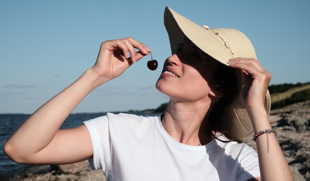 Una mujer está descansando en la playa en un clima soleado y comiendo cerezas