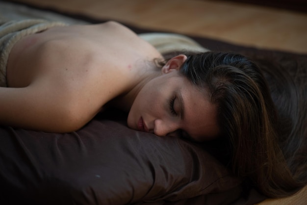 Una mujer está durmiendo en una cama con la cabeza hacia abajo y su cabello es negro.