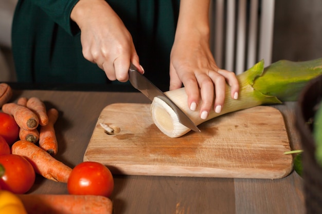 La mujer está empezando a cortar una cebolla en la mesa.