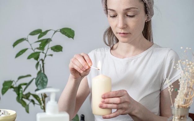 La mujer está encendiendo velas para crear un ambiente relajante armonía y equilibrio Concepto de aromaterapia rituales matutinos y vespertinos cuidado de la piel