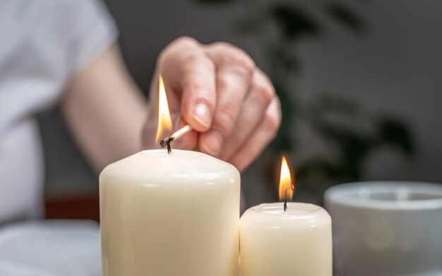 La mujer está encendiendo velas para crear un ambiente relajante armonía y equilibrio Concepto de aromaterapia rituales matutinos y vespertinos meditaciones Cerrar