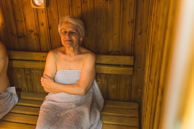 Una mujer está envuelta en una toalla en una sauna.