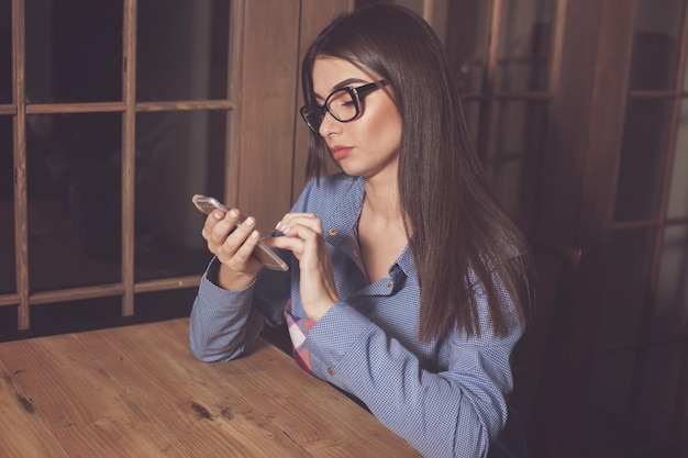 La mujer está escribiendo algo en su teléfono en la mesa