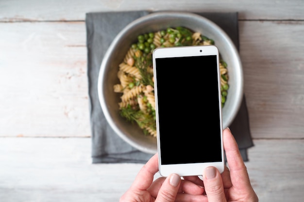 Una mujer está fotografiando un primer plano de ensalada cocida