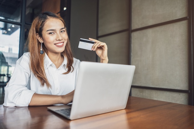 la mujer está haciendo compras en línea con tarjeta y computadora.