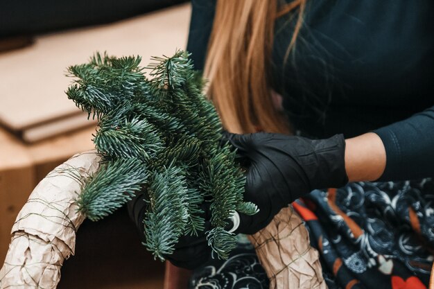 La mujer está haciendo corona de Navidad.