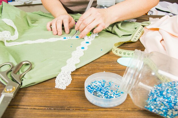 Una mujer está haciendo joyería un taller casero Manos femeninas que crean un accesorio con cuentas y cintas Belleza creatividad el concepto de artesanía