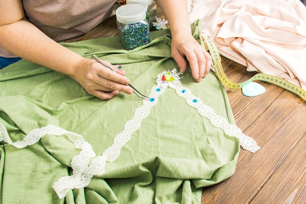 Una mujer está haciendo joyería un taller casero Manos femeninas que crean un accesorio con cuentas y cintas Belleza creatividad el concepto de artesanía