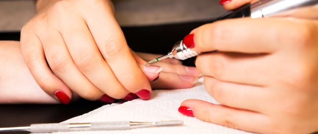 La mujer está haciendo una manicura. Procedimientos de salón a domicilio. Hermosas manos y uñas.