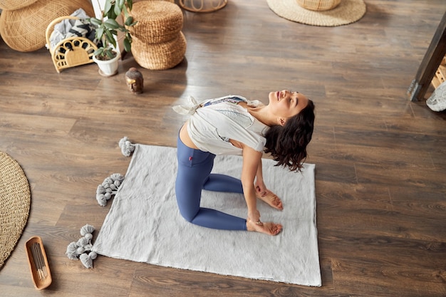 La mujer está haciendo yoga y prácticas meditativas en una habitación decorada al estilo de bali