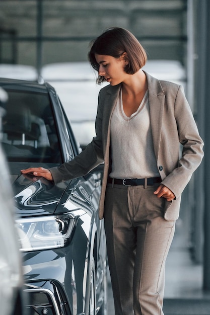 La mujer está en el interior cerca de un automóvil nuevo en el interior