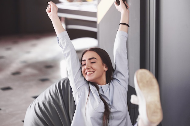 La mujer está jugando en la consola y está feliz de ganar, levanta los brazos y sonríe.