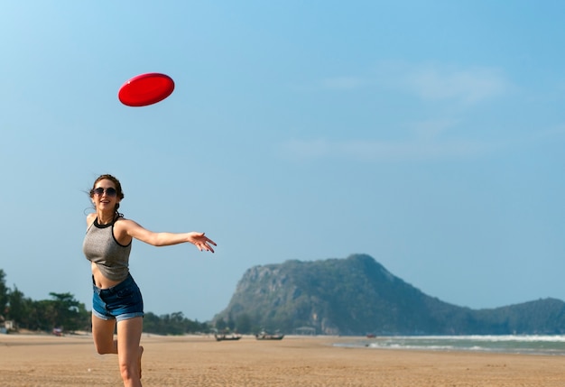 Una mujer está jugando frisbee en la playa