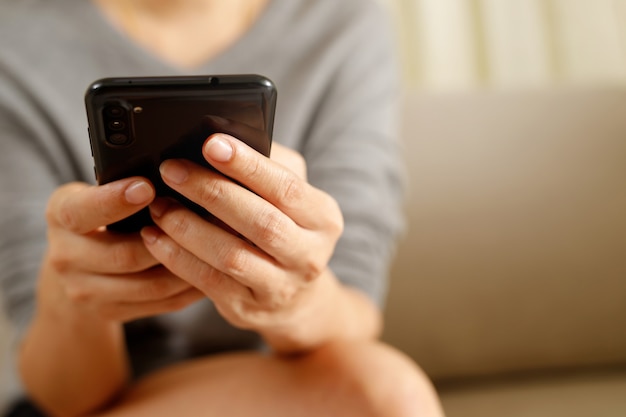 La mujer está jugando en el teléfono inteligente.