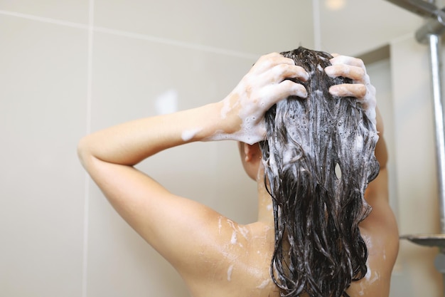 La mujer se está lavando el cabello con champú x9