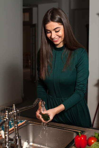 La mujer está lavando un pepino verde