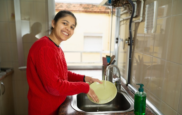 Una mujer está lavando un plato en un fregadero de la cocina