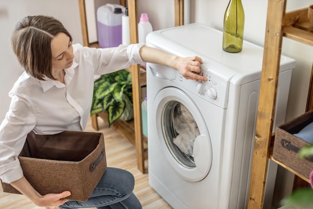 Una mujer está lavando ropa en una lavadora en una sala de lavandería