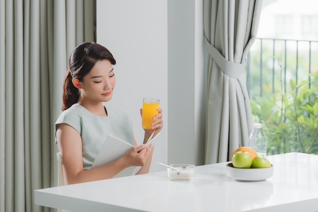 La mujer está leyendo un libro y desayunando