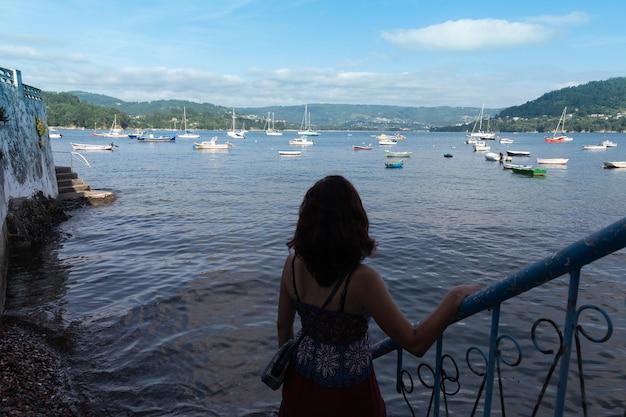 Una mujer está mirando los barcos en el agua en Redes Galicia España