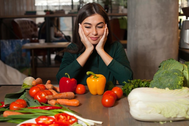 La mujer está mirando verduras en la mesa