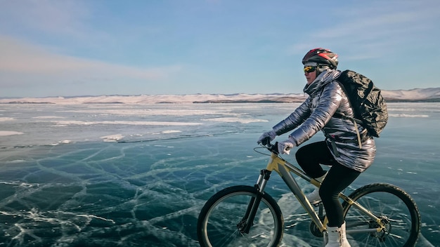 Mujer está montando bicicleta en el hielo Los neumáticos en bicicleta están cubiertos wi