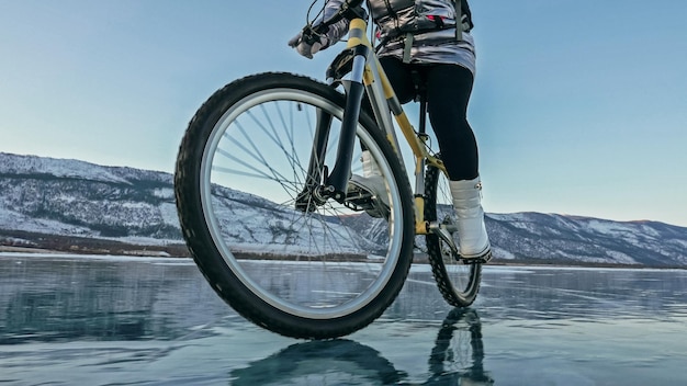 La mujer está montando en bicicleta en el hielo La niña está vestida con una mochila de ciclismo de chaqueta plateada