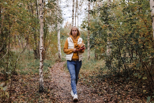 La mujer está en el parque de otoño Paseo por el bosque Atmósfera otoñal