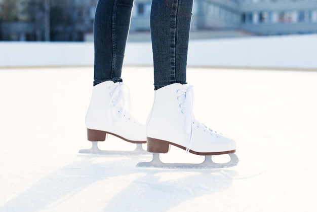 La mujer está patinando sobre hielo en la pista de cerca