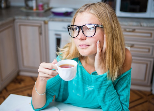 La mujer está perdida en sus pensamientos y bebiendo café.