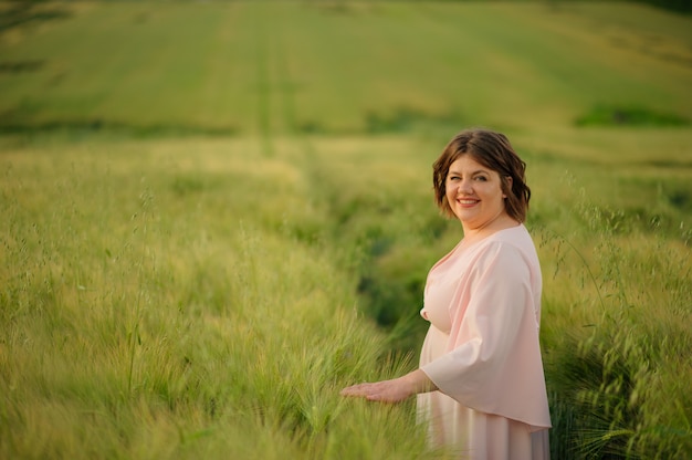 Una mujer está de pie en un campo de trigo verde