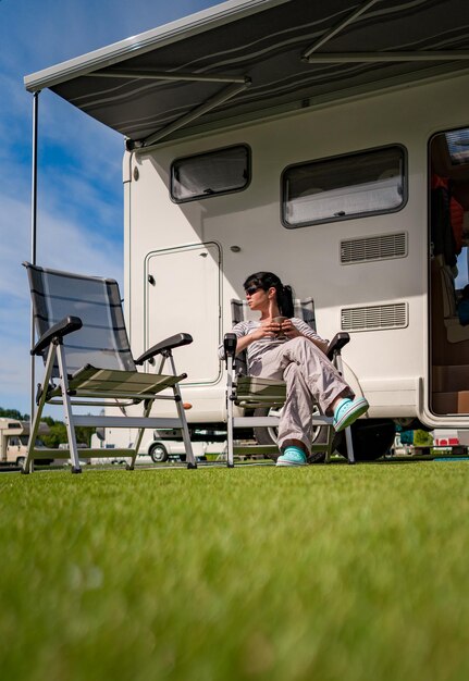 La mujer está de pie con una taza de café cerca de la caravana. Vacaciones en coche caravana. Viajes de vacaciones en familia, viaje de vacaciones en autocaravana RV