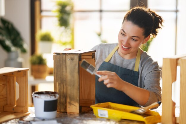 La mujer está pintando una caja de madera.