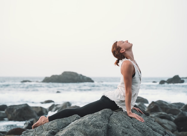 La mujer está practicando yoga y meditación en la hermosa playa salvaje